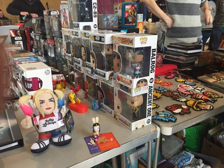 Zoom sur un stand où l'on voit des figurines, des mugs et des DVD